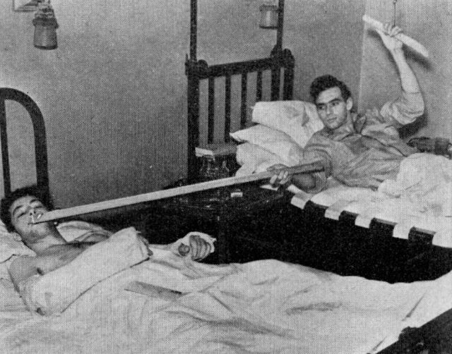 Patient in bed being 'fed' his daily cigarette ration, 1938