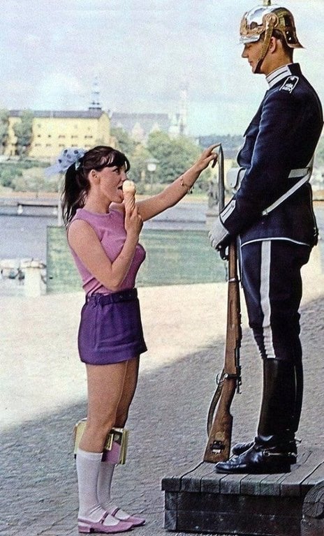 A girl licks ice cream and plays with the tip of the guns bayonet to try and elicit a reaction from a royal guard in Sweden in 1970.