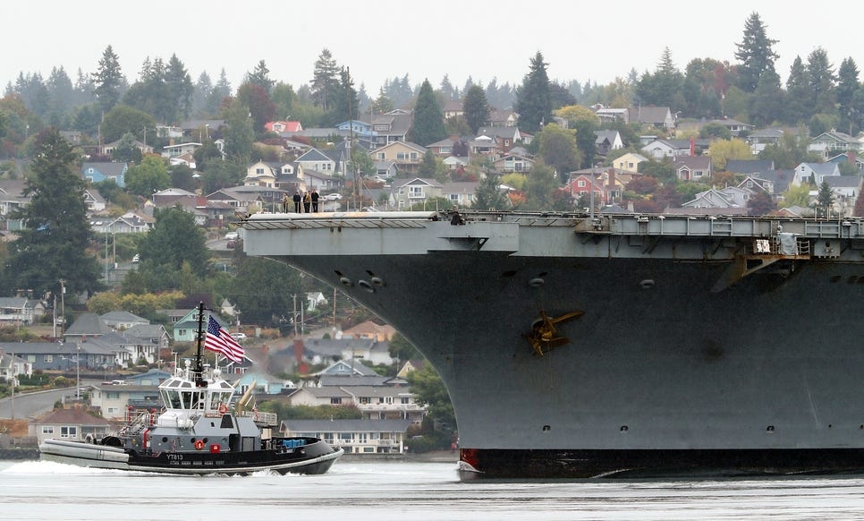 The Navy tug Sentinel helps guide the USS Nimitz past the Mannette neighborhood of Bremerton as it returns to Naval Base Kitsap on Sunday, Sept. 24, 2023.