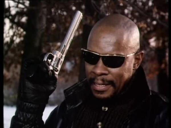 Avery Brooks as Hawk in Spencer: For Hire, wearing black shades and brandishing a revolver.