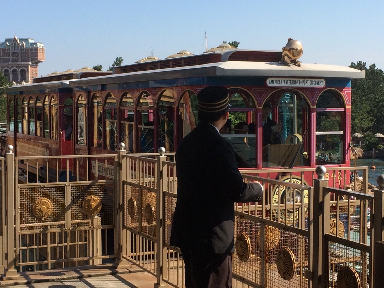 A station attendant watching as a train set on the Tokyo DisneySea Electric Railway pulls into Port Discovery Station.