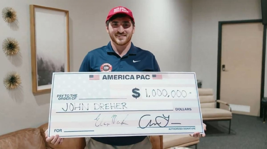 Guy holding a giant winner&#39;s check with his name, John Dreher, where the amount should be. 