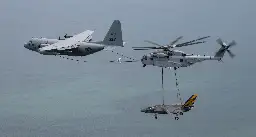 Check out this Navy tanker that's refueling a Marine helicopter that's carrying a Navy fighter