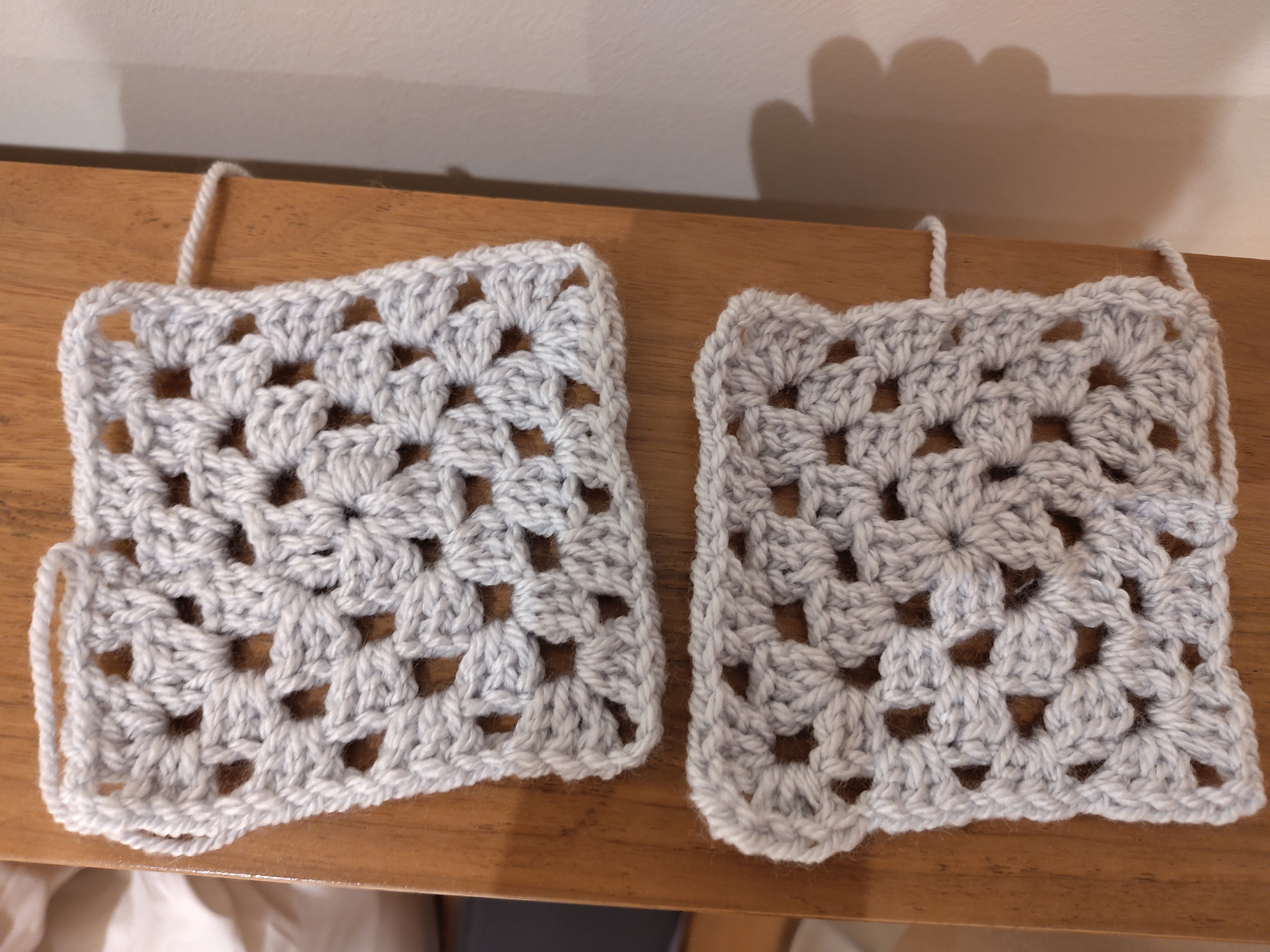 Two pale grey granny squares. 