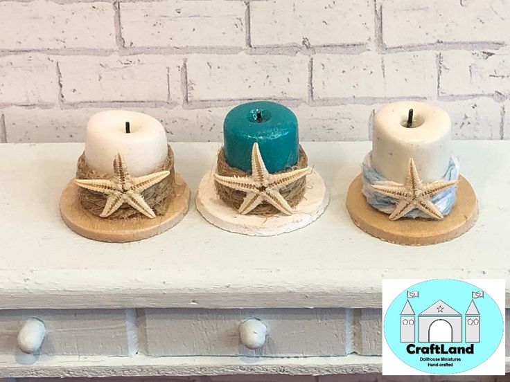 3 beach themed candles, 2 cream, one blue, each with a starfish tied onto them with natural twine-like material