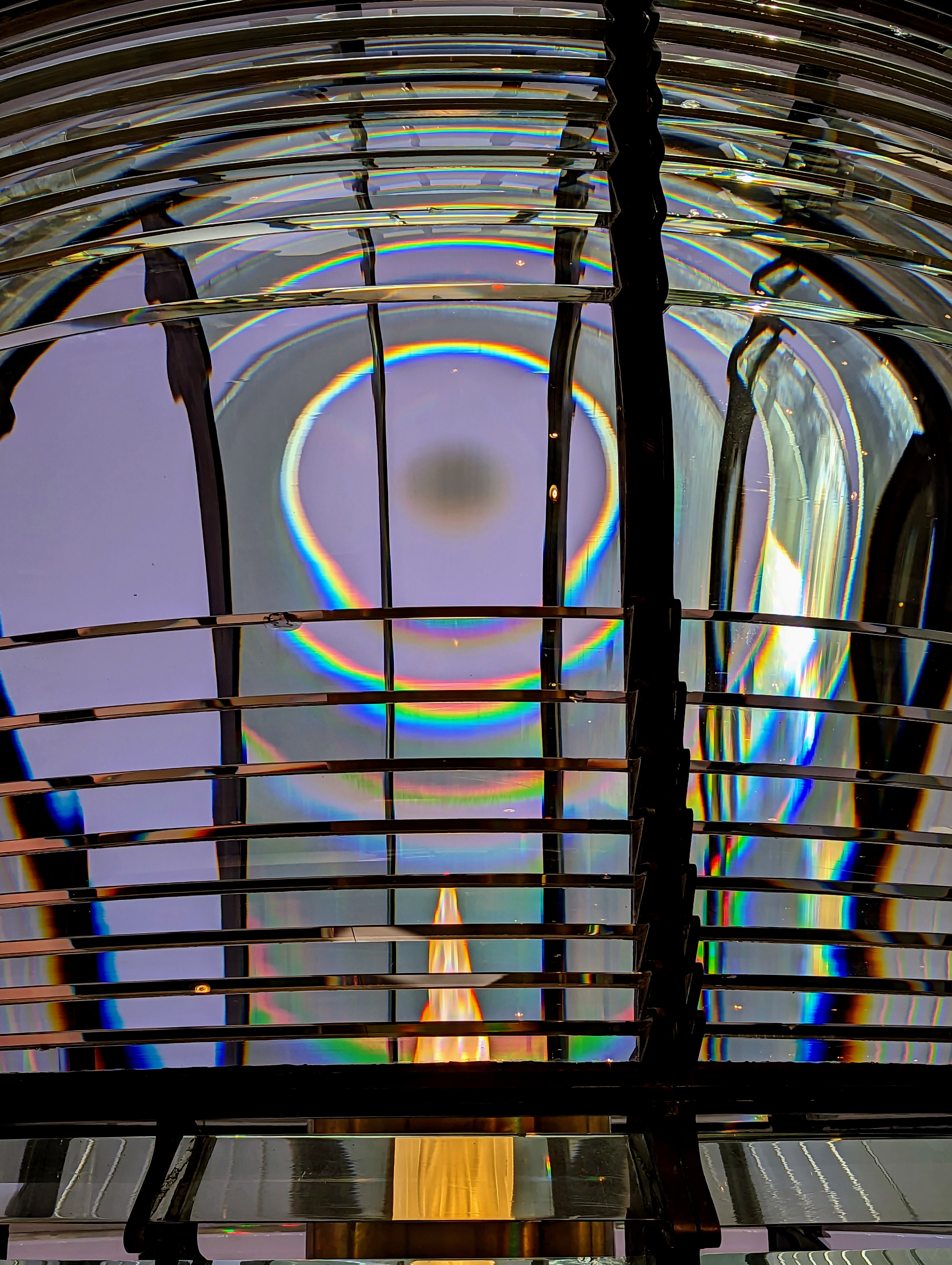sunlight creating rainbows within an old lighthouse lamp and lens