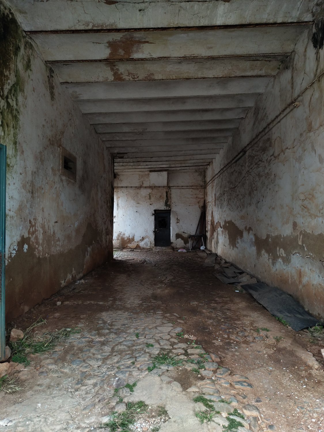a picture of the inside of an abandoned building entrance with a door at the back wall