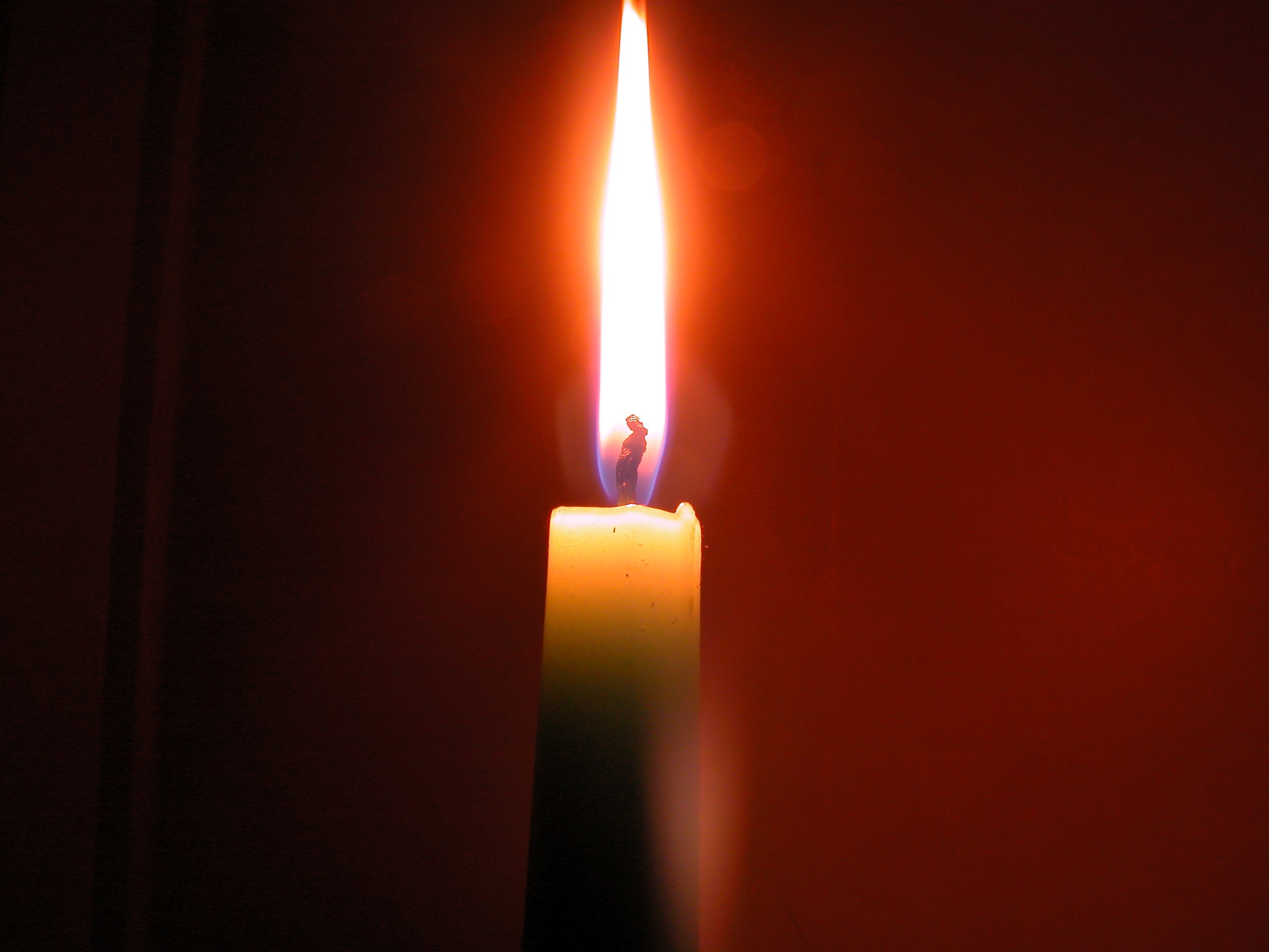 Picture of a candle flame with a blue glow at the bottom and yellow at the top. 