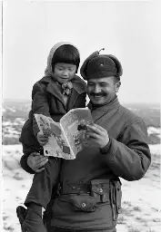 Soldier of the Turkish Brigade showing American comics to a girl, 1951, Korean War