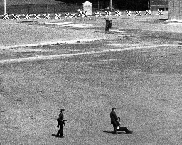 East German guards carry away a refugee wounded by machine-gun fire after trying to escape East Berlin, 1971