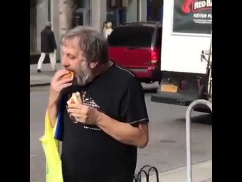 photo of slavoj zizek on a sidewalk absolutely devouring a hotdog